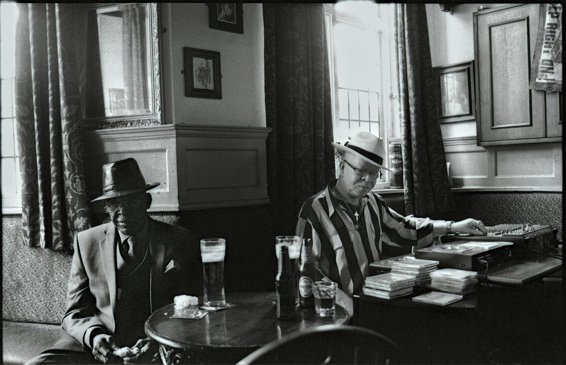 Two men in hats sharing a drink in a pub