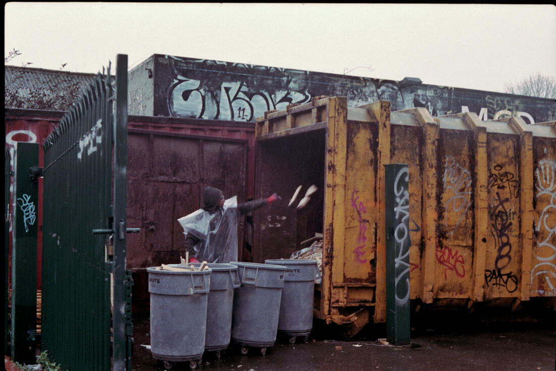Man loading waste into a graffiti-covered skip