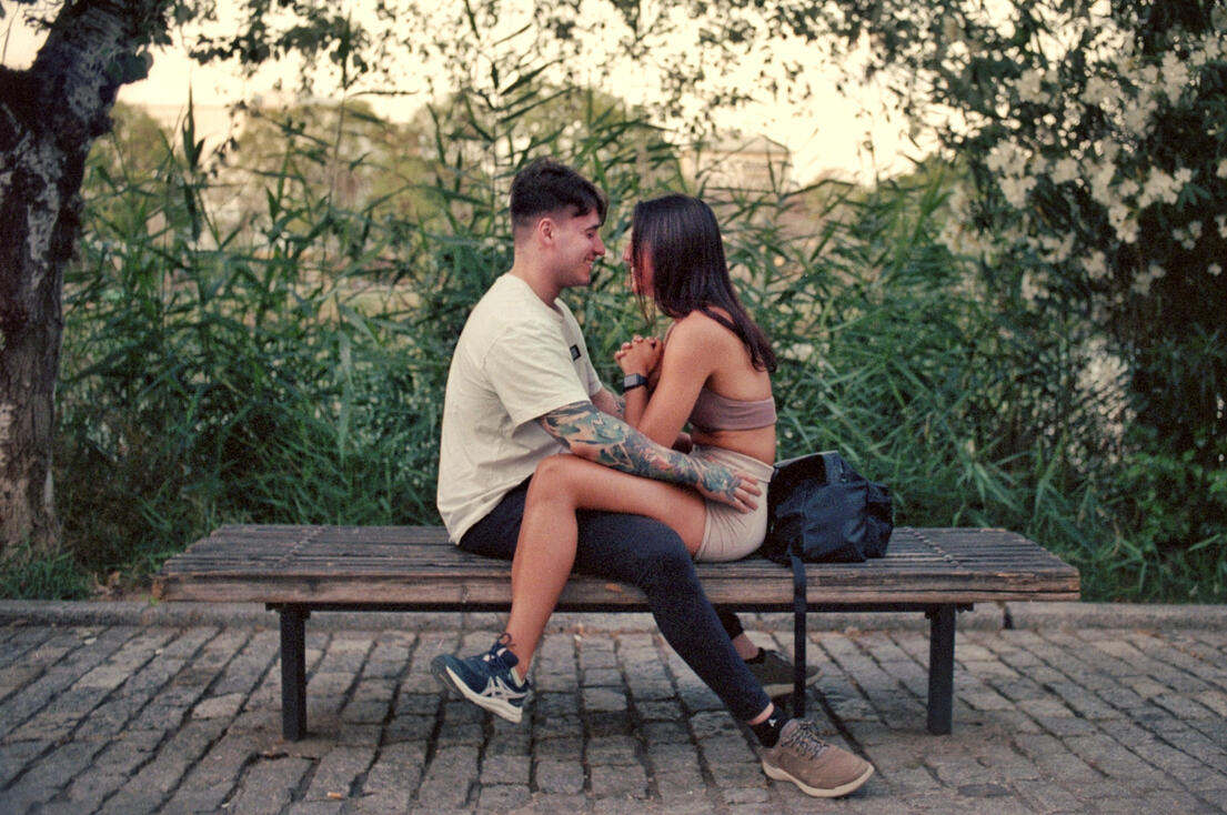 Couple embracing on a riverside bench at dusk, Seville