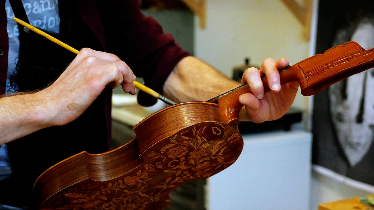 Luthier's hands varnishing the scroll of a violin