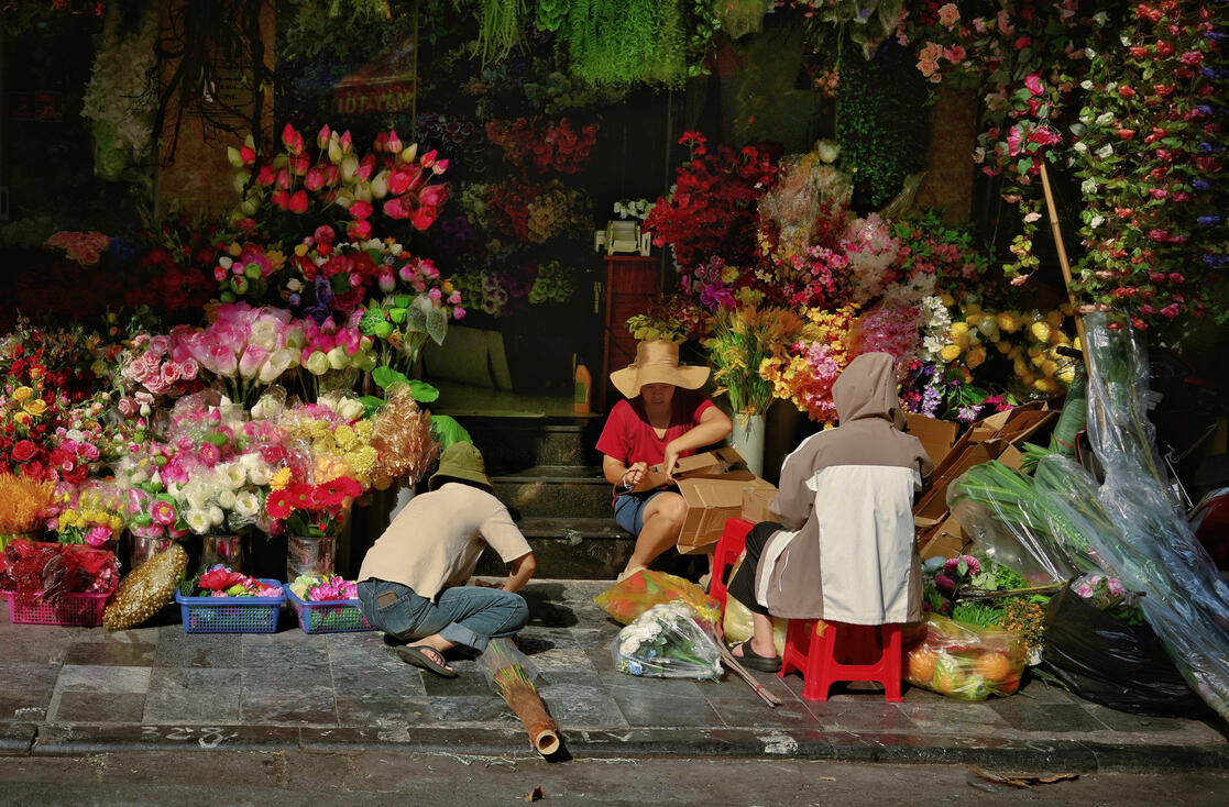 Flower sellers surrounded by roses at a Hanoi night market