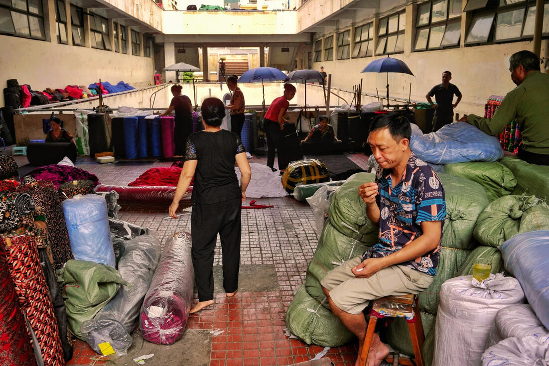 Trader resting among fabric rolls at a Hanoi wholesale market