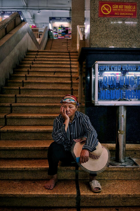 Tired market trader resting on steps at Dong Xuan market, Hanoi