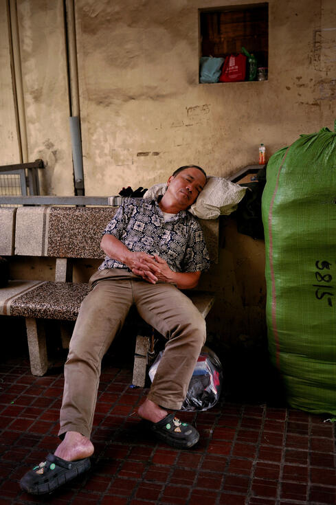 Man asleep on a stone bench in a Hanoi market