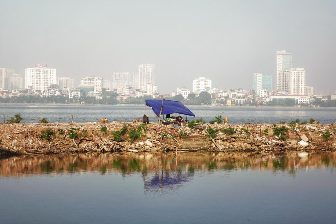 Fisherman's shelter on West Lake at dawn, Hanoi skyline behind